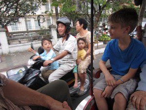 Braxton engaging in cross-cultural exchange from back of tuk tuk, Phnom Penh, Cambodia